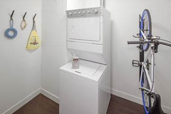 A white oven is in a corner of a room with a bicycle hanging on the wall.